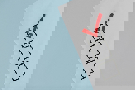 A red check mark placed inside the top box of a checklist printed on white paper against a light blue background.