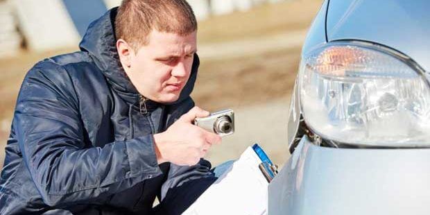 insurance adjuster taking photos of a wrecked car